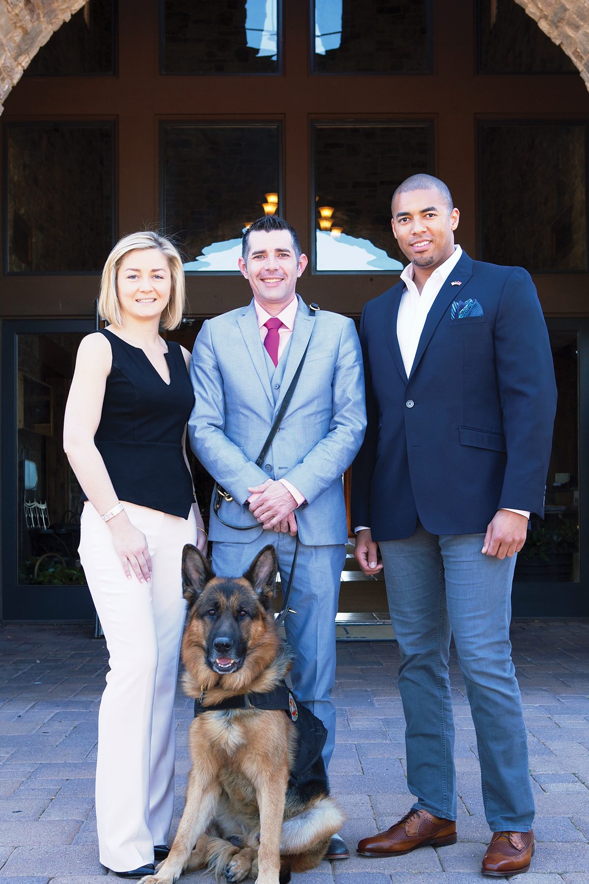 Chrissy Faulkner, deputy director of The Battle Buddy Foundation, stands on the left; Kenny Bass and Atlas are in the center; co-founder Joshua Rivers stands on the right.