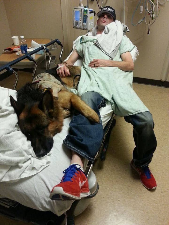 Atlas lying close against Kenny Bass in a medical setting.