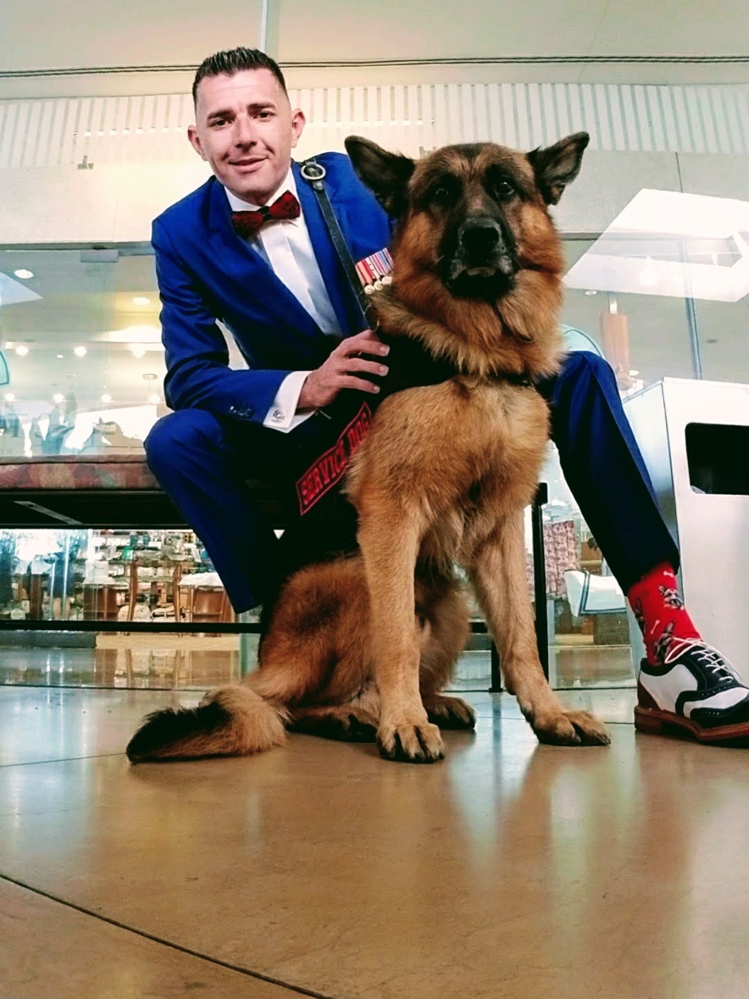 Kenny Bass in formal attire crouched beside Atlas during a public appearance in 2017.