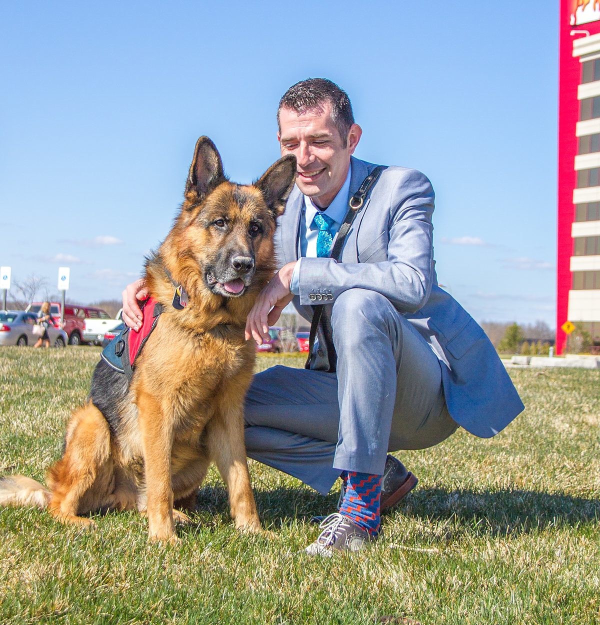 Kenny Bass with Atlas, a German Shepherd service dog, outdoors.